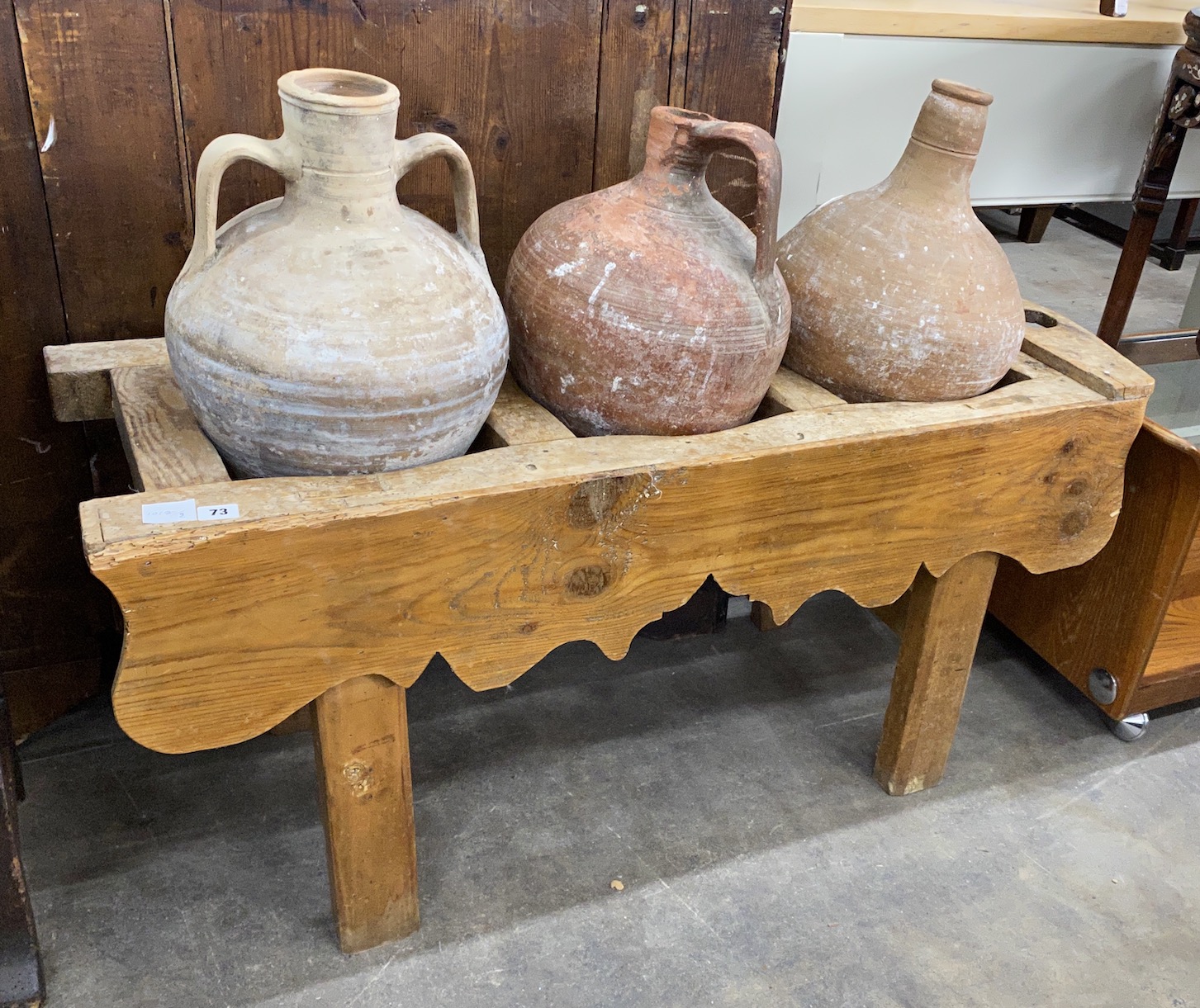Three Mediterranean pottery olive jars on a rectangular pine stand, stand width 116cm, depth 41cm, height 56cm